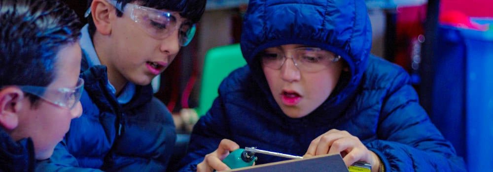 Alumnos con gafas de seguridad trabajan juntos en una actividad